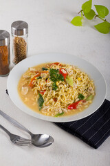 a bowl of hot noodle with boiled egg, chicken, slice chili in white bowl on white background texture