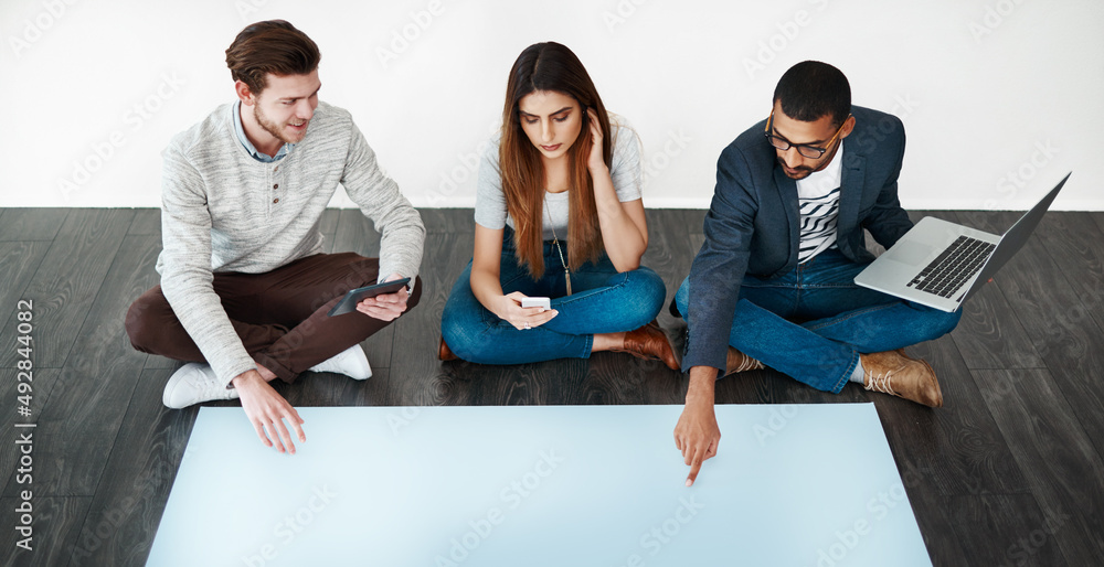Poster it all began with a brainstorm. studio shot of a group of young people sitting on the floor and work