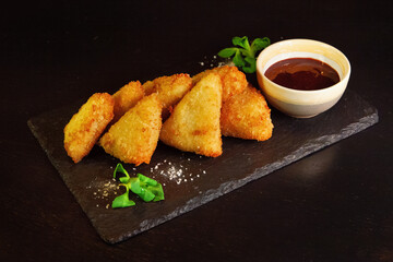 Golden delicious fried nuggets with sauce on a dark background