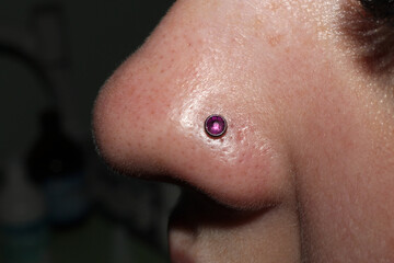 Fototapeta premium Girl's nose piercing. Purple crystal.