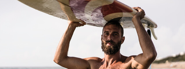 Horizontal banner or header with surfer holding his surfboard on the head - Hipster man standing on...