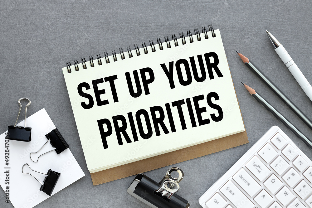 Aufkleber set up your priorities text on an open notepad. on a gray work table