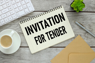 notepad with text near coffee cup and white keyboard INVITATION FOR TENDER