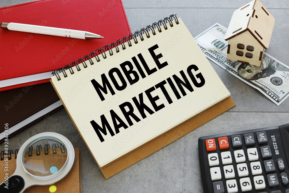 Poster work table with money and figurine of the house on the table and notepad with text mobile marketing