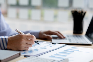 Businessman check to financial documents, he owns a startup company, he sits checking the company's financial summary prepared by the finance department. Management concept of startup company.