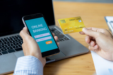 A person is holding a credit card to pay online, credit card payments can be used on both laptop computers and mobile phones. Concept of payment for goods and services via credit card.