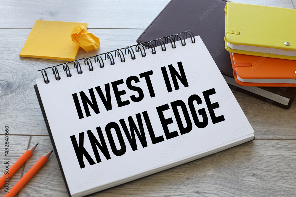 Poster invest in knowledge. notepad with text on scattered notepads on the work table. stickers and colorfu