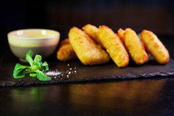 Golden delicious fried nuggets with sauce on a dark background