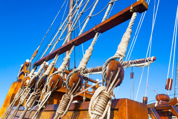 Part of an old sailing wooden ship with a rope ladder with pulleys, knotted ropes and wooden...