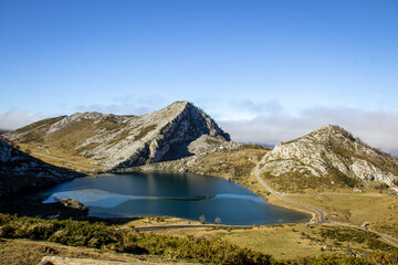 Fototapeta na wymiar Paisaje montañoso adornado por un lago semicongelado. Cielo azul y reflejos del sol .Lagos de Covadonga 