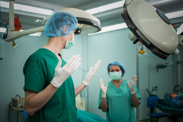 Asian team doctor surgeon Working in the operating room, wearing medical gloves to prepare for the surgical operation, to people health care and cosmetic surgery concept.