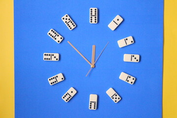 Clock making with dominoes, dominoes on blue background.