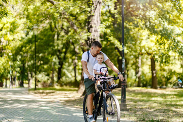A father and son enjoying the bike ride in a park on weekend.