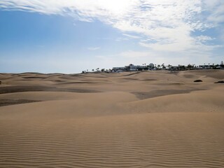 Hoteles y Resorts en la distancia detrás de las dunas costeras de la playa de Maspalomas, isla de Gran Canaria, España. Paisaje desértico y costero diseñado por el efecto del viento sobre la arena.