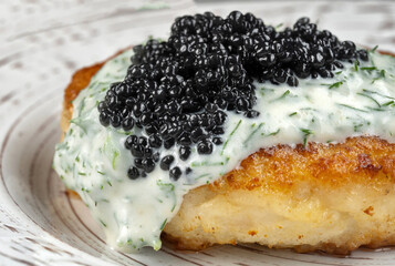 Draniki with black caviar and dill sauce on a beautiful plate.