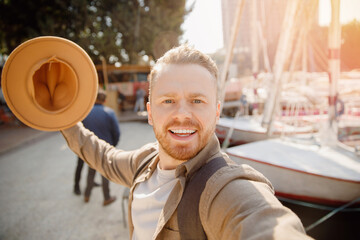 Young man driver in hat takes selfie photo background yacht summer day, concept rent for travel boat