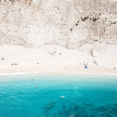 Beach under a cliff with azure sea. aerial view at beautiful coast. Aerial view of turquoise ocean wave reaching the coastline. 