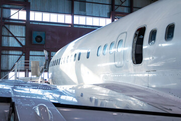 Close-up of a white passenger jet plane in the hangar. Airplane under maintenance. Checking mechanical systems for flight operations