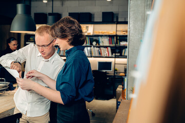 Two young male and female engineer, architect colleagues coworker working to discuss about blueprint, finding solution, analyze problems of new engineering project in modern office, Teamwork concept