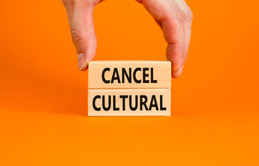 Cancel cultural symbol. Concept words Cancel cultural on wooden blocks on a beautiful orange table orange background. Businessman hand. Business and cancel cultural concept, copy space.