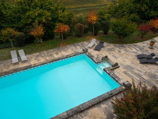 Top view of a swimming pool with sun loungers in a garden.
