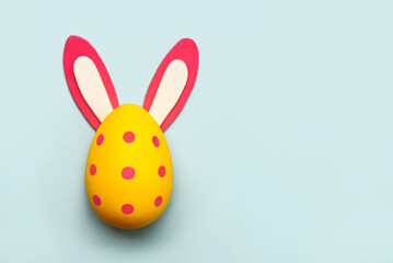 Happy Easter. Yellow easter painted egg with rabbit ears and copy space