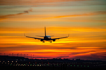 Fototapeta na wymiar Landing of an airplane with a strong reddish sunset