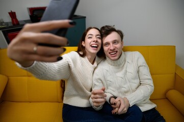 a young married couple at home. They sit on the couch and take selfies 