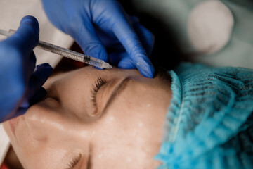 A cosmetologist injects a syringe into a patient, Botox