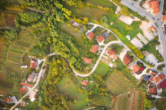Aerial photography of mountainous terrain with a narrow road winding between houses, gardens and vegetable gardens.