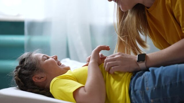 mother tickle daughter. happy family a playing on the bed at home. happy family home kid dream concept. mom tickles daughter play laugh fun. mom tickle lifestyle daughter lying on the bed