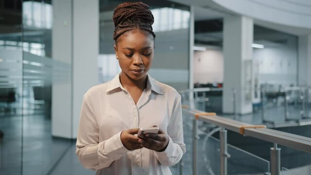 African Serious Focused Female Office Manager Woman Boss Leader With Modern Smartphone In Office Company Corporate Space Business Center Indoors Typing Texting Phone. Businesswoman With Telephone App