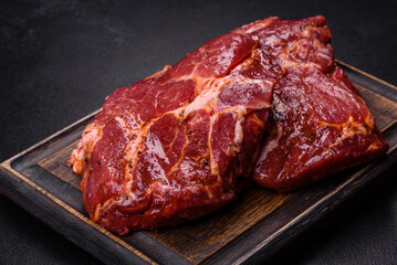 Raw organic marbled beef steaks with spices on a wooden cutting board