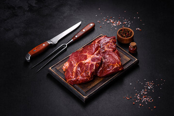 Raw organic marbled beef steaks with spices on a wooden cutting board