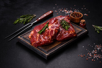 Raw organic marbled beef steaks with spices on a wooden cutting board