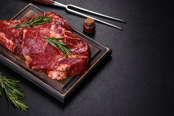 Raw organic marbled beef steaks with spices on a wooden cutting board