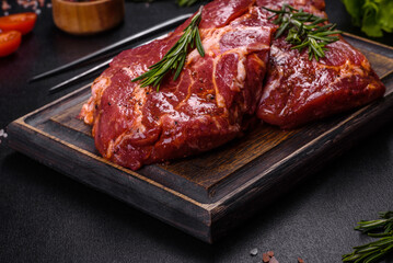 Raw organic marbled beef steaks with spices on a wooden cutting board