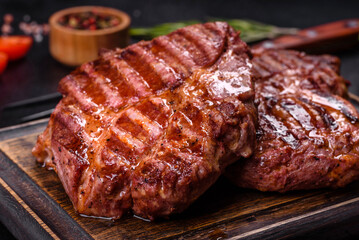Grilled ribeye beef steak, herbs and spices on a dark table