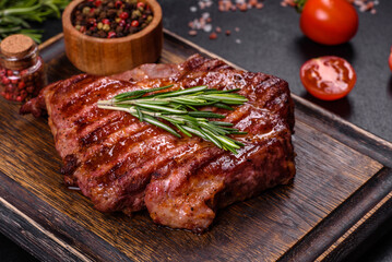 Grilled ribeye beef steak, herbs and spices on a dark table