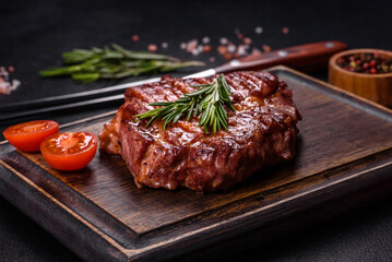 Grilled ribeye beef steak, herbs and spices on a dark table