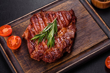 Grilled ribeye beef steak, herbs and spices on a dark table