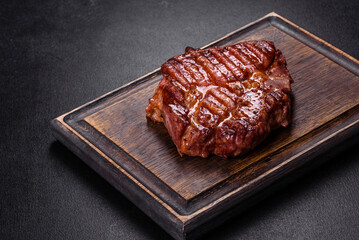 Grilled ribeye beef steak, herbs and spices on a dark table