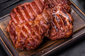 Grilled ribeye beef steak, herbs and spices on a dark table