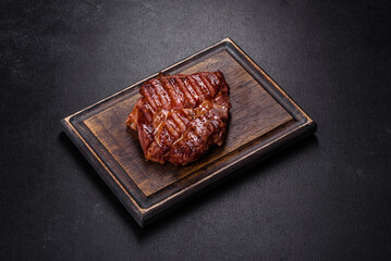 Grilled ribeye beef steak, herbs and spices on a dark table