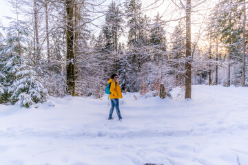 Winterwandern  im Winterwald 
Frau mit gelber Jacke und Rucksack