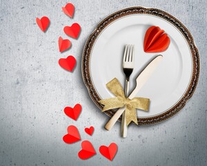 Valentines day table setting on a background. plate, cutlery and red hearts, romantic dinner concept
