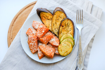 Grilled vegetables baked in the oven with Parmesan cheese on textile napkin. Pieces of pumpkin, eggplant, Aubergine and zucchini with Parmesan. Healthy vegan organic meal. Superfood for immune system.