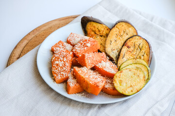 Grilled vegetables baked in the oven with Parmesan cheese on textile napkin. Pieces of pumpkin, eggplant, Aubergine and zucchini with Parmesan. Healthy vegan organic meal. Superfood for immune system.