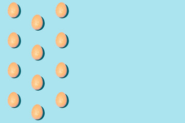 Pattern made of orange eggs on pastel blue background. Minimal Easter or food concept. Copy space.