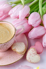 Vintage pink coffee cup, tulip flowers and french sweet cookies macarons macaroons  on marble background.